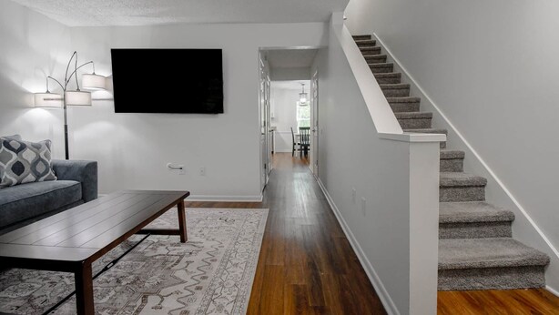 Un couloir avec un escalier, un canapé, une table basse et un tapis.