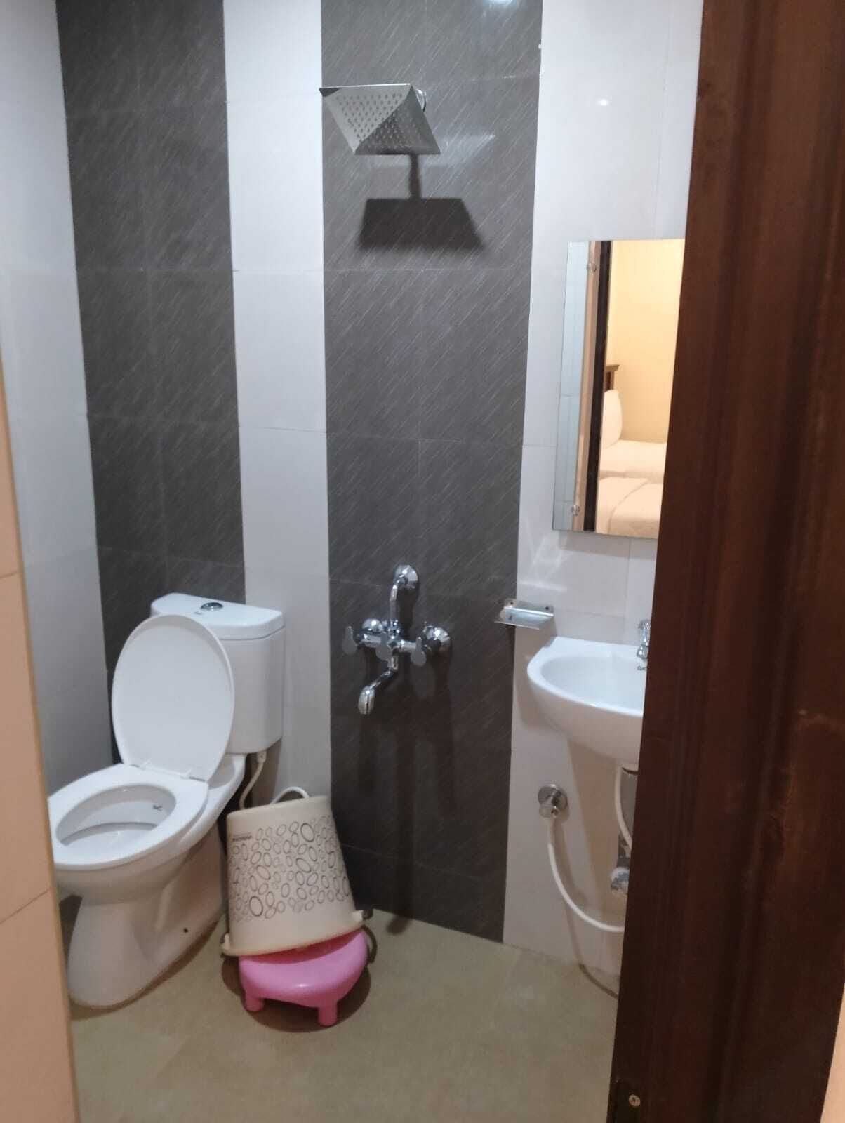 Un baño con inodoro, bidé, lavabo y un taburete pequeño.