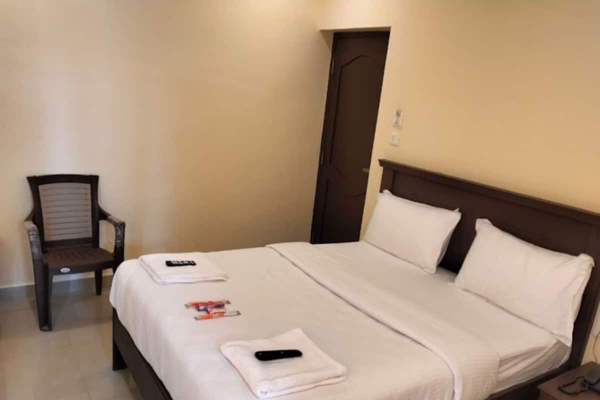 A hotel room with a bed, a chair, and a door.