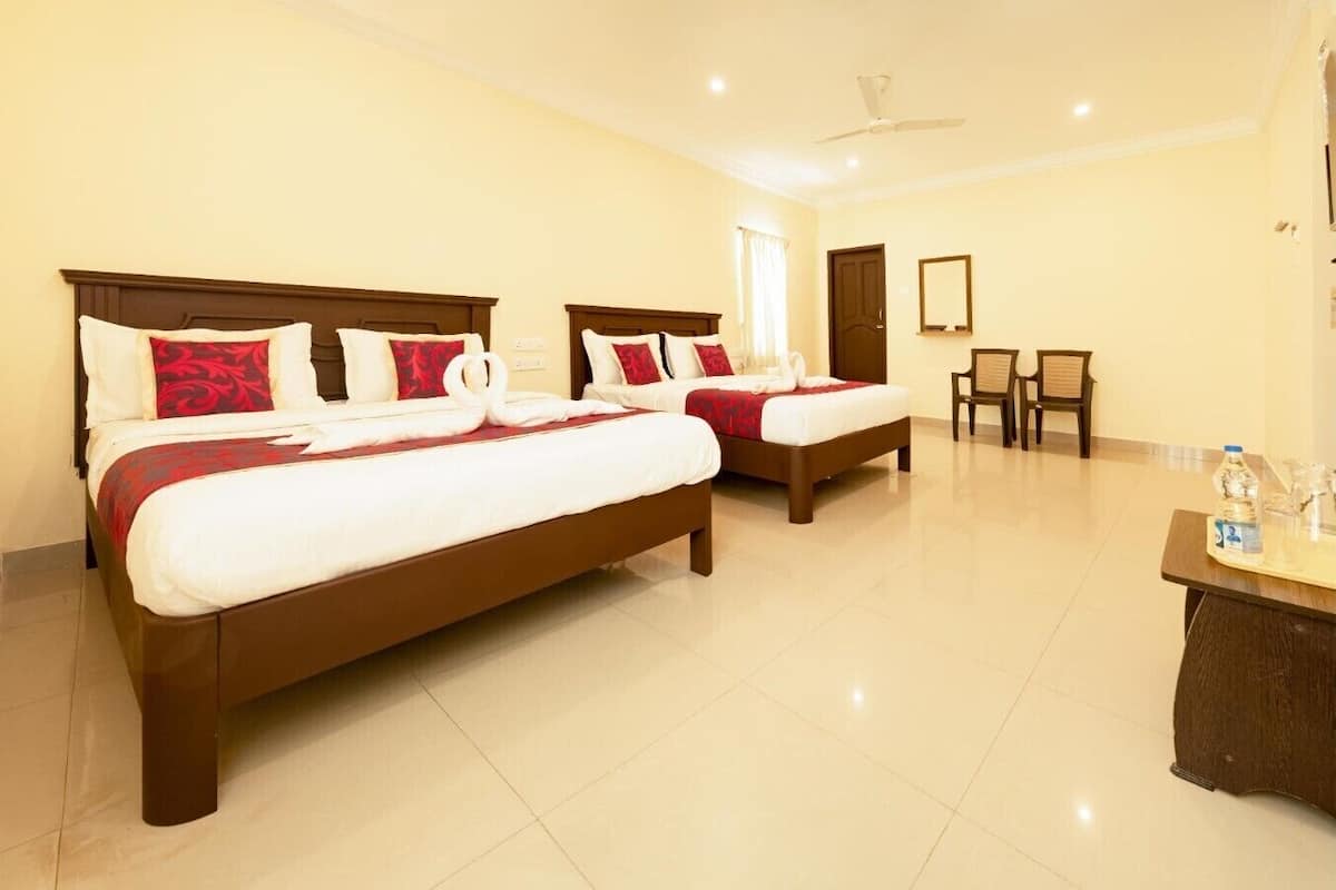 A hotel room with two beds, a desk with a water bottle, and a chair.