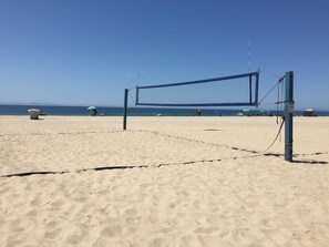 Ein Beachvolleyballnetz an einem sandigen Strand unter blauem Himmel.
