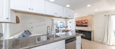 A modern kitchen with white cabinets, granite countertops, a stainless steel sink, and a dishwasher.