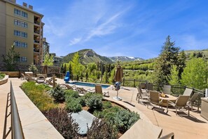 A pool area with lounge chairs, a hot tub, and a view of mountains. - Upscale Riverfront Condo- BC Gondola, Dog Friendly (Avon)