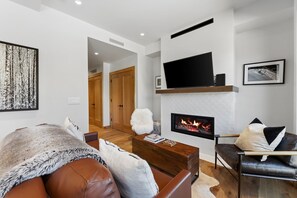 Ein modernes Wohnzimmer mit Kamin, Ledersofa und Flachbildfernseher.