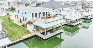 Ein Haus am Wasserufer mit einer Terrasse, einer überdachten Veranda und einem Steg, der ins Wasser führt.