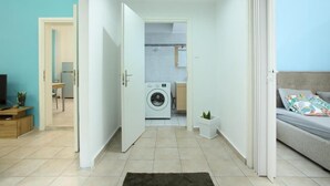 A modern apartment with a laundry area, a sofa, and a small plant.