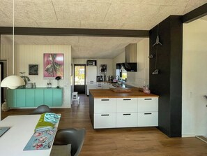 Eine moderne Küche mit einer Holzinsel, weißen Schränken und einer Türkis-farbenen Akzentwand.