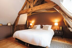 Ein Schlafzimmer mit Holzboden, einem Bett mit weißen Leinen, zwei Nachttischen mit Lampen und einem gemusterten Teppich.