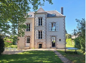 Ein zweistöckiges Haus mit Ziegelaußenwand, zahlreichen Fenstern mit Fensterläden, einer Haustür und einem kleinen Vorgarten mit Trampolin.