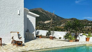 A pool with clear water, a white building, and a mountain in the background. - Design rustic villa in Alcaucín with pool (29713, Málaga)