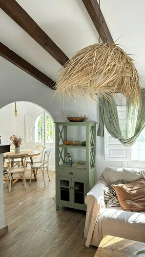A room with a green cabinet, a hanging basket, a sofa, and a dining area with chairs and a table. - Design rustic villa in Alcaucín with pool (29713, Málaga)