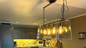 Una cocina moderna con gabinetes grises, una isla central e iluminación colgante.