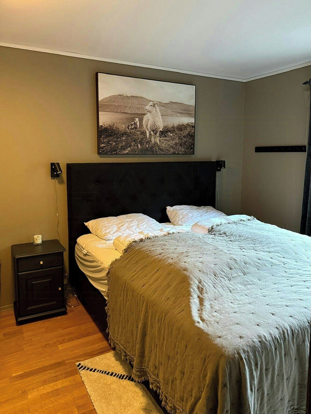 Un dormitorio con una cama, una mesita de noche, una lámpara y un cuadro en la pared.
