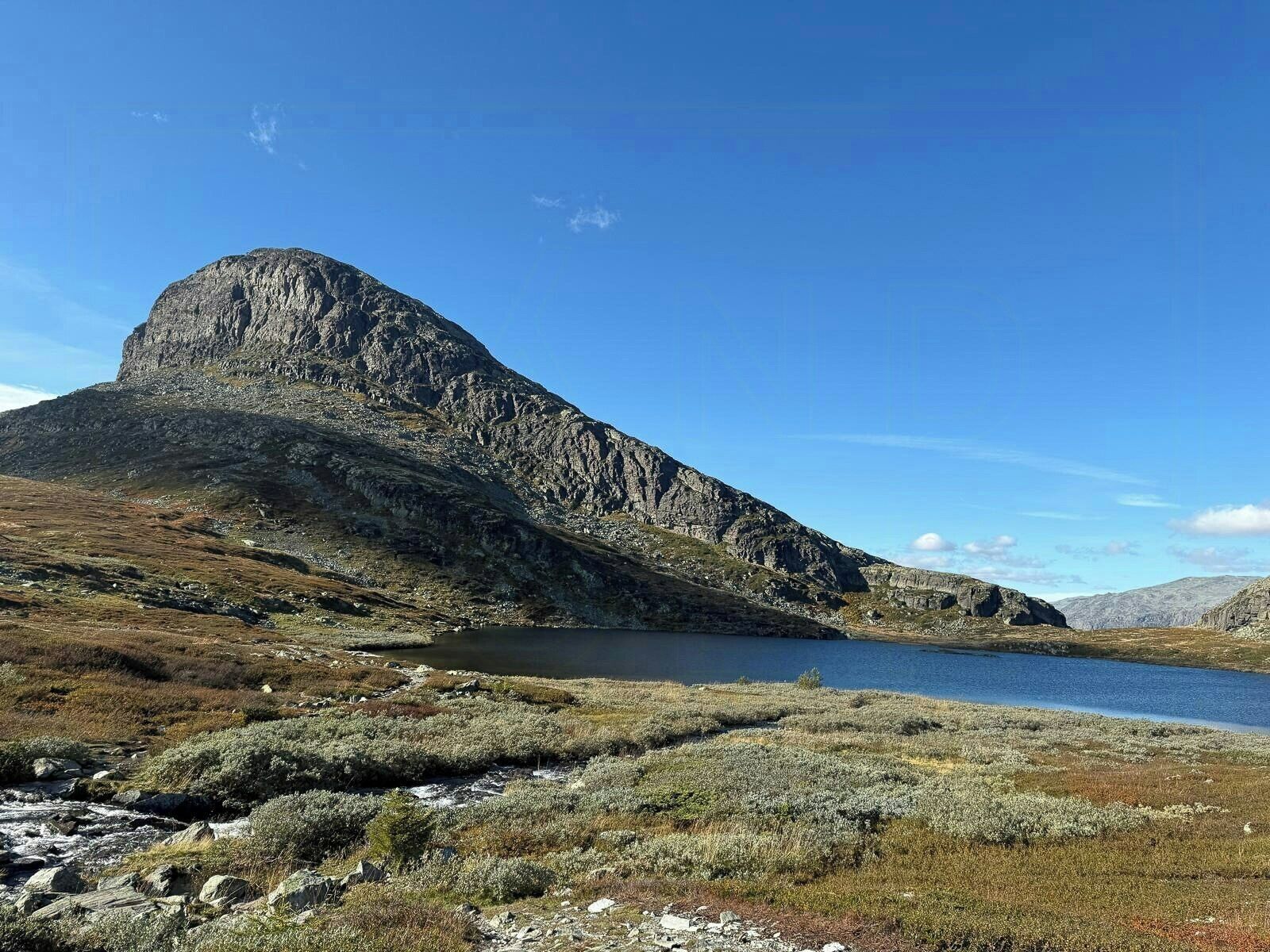 Een bergachtig landschap met een meer en schaarse vegetatie.