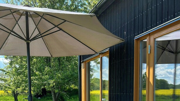 Een terras met een tafel, stoelen, een parasol en een bloempot.