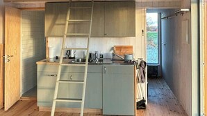 Een kleine keuken met een houten ladder, een spoelbak en een raam.