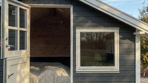Eine kleine, eingeschossige Holzhütte mit Schlafkoje, Fenster und Tür.