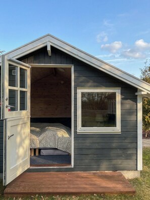 A small, single-story cabin with a loft bed, a window, and a door. - Summer house near beach and nature (Væggerløse)