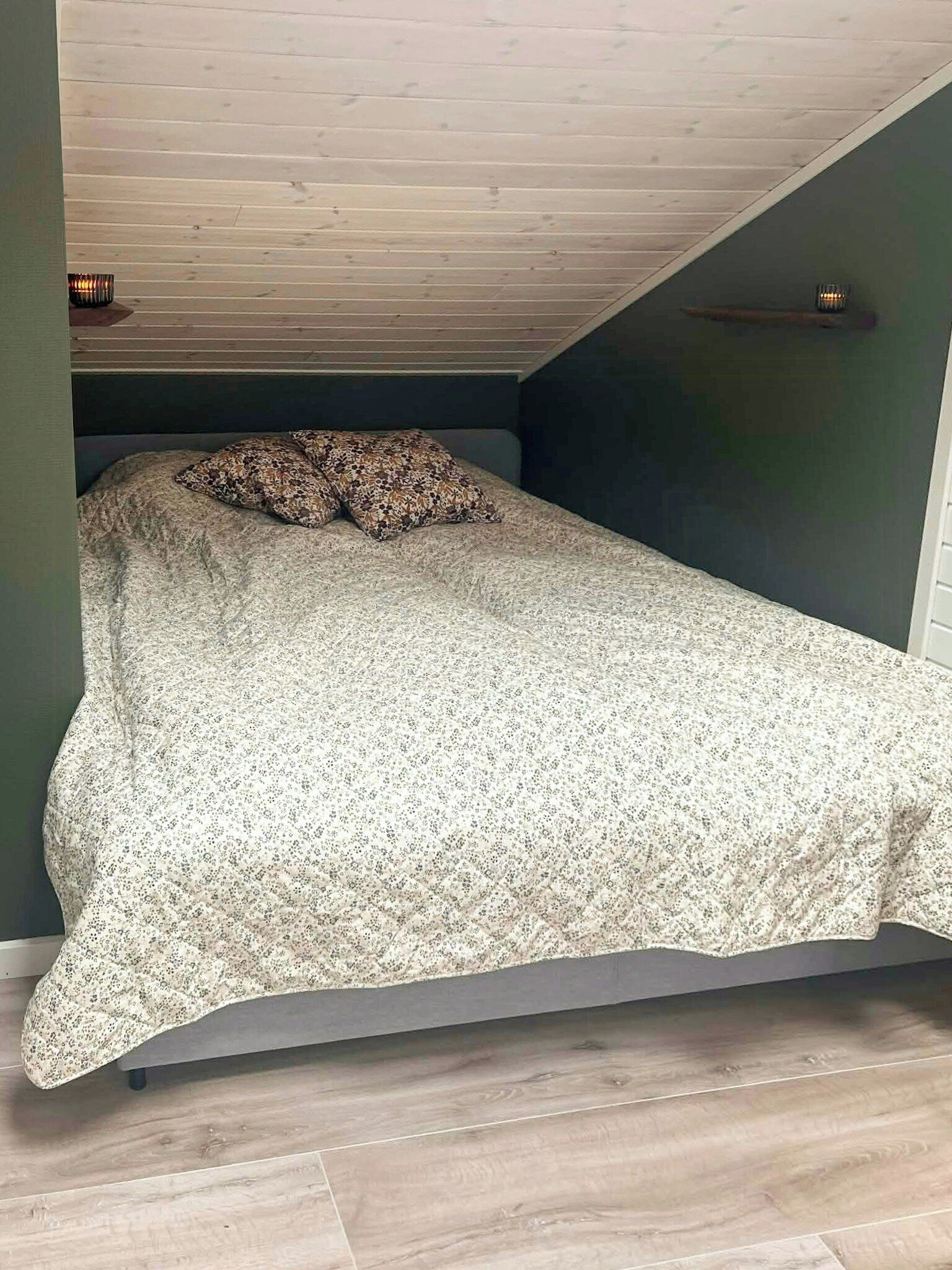 A bedroom with a bed, a wooden ceiling, and a green wall.