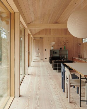 Ein modernes Interieur mit Holzböden, einer Essecke und einer Küche.