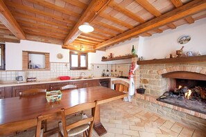 Una cocina con una mesa de madera, una chimenea de piedra y un revoque de azulejos.