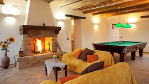 A cozy living room with a fireplace, a pool table, and a sofa. - Historic villa with pool in Marche hills (Sant'Angelo in Pontano)
