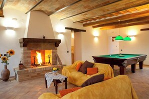 Ein gemütliches Wohnzimmer mit Kamin, Billardtisch und einer Couch.