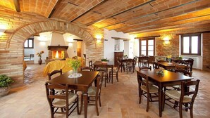 A spacious dining area with brick walls, a fireplace, and multiple tables and chairs. - Historic villa with pool in Marche hills (Sant'Angelo in Pontano)