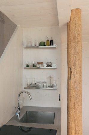 A kitchen with a stainless steel sink, wooden shelves with glass containers, and a wooden beam. - Studio with balcony at Mühlenberg Werder (Werder (Havel))