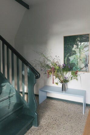 A staircase with a metal handrail, a white bench, and a vase with flowers. - Studio with balcony at Mühlenberg Werder (Werder (Havel))