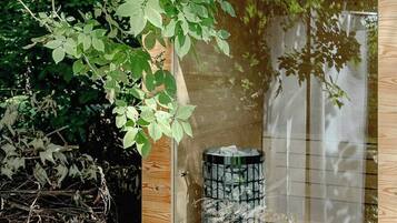 Estructura de madera con cerramiento de vidrio, un objeto cilíndrico en su interior y un nido en el exterior.