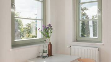 A room with two windows, a white table, and two wooden chairs.