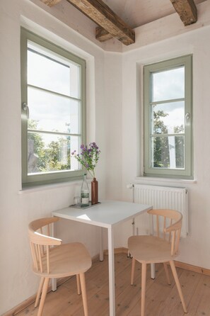 A room with two windows, a white table, and two wooden chairs. - Studio with balcony at Mühlenberg Werder (Werder (Havel))