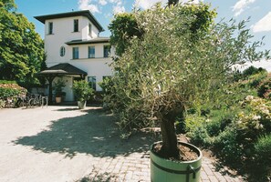 A building with a paved courtyard, a potted tree, and a bicycle. - Studio with balcony at Mühlenberg Werder (Werder (Havel))
