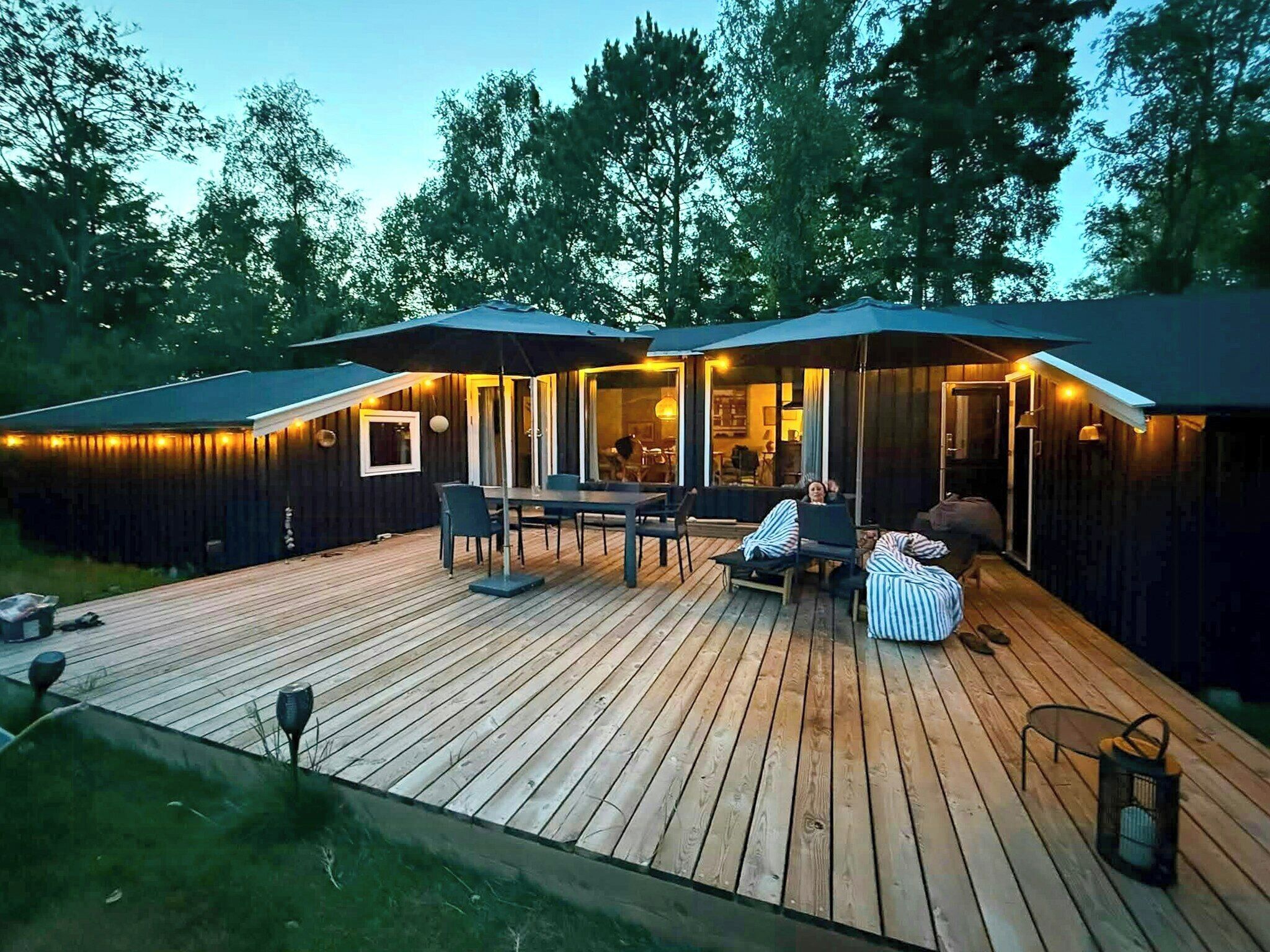 A wooden deck with outdoor furniture, a covered seating area, and a view of the surrounding forest.