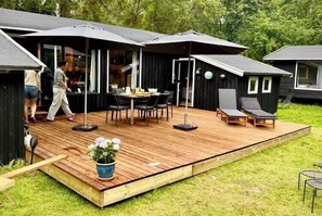 Eine moderne Terrasse im Freien mit Esstisch und Stühlen, umgeben von Sonnenschirmen und einer Topfpflanze.