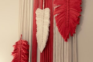 Pared decorada con tres colgadores de macramé en rojo y blanco.