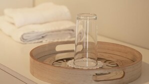 Ein Holztablett mit einem Glasbehälter auf einem Tisch, ein weißes Handtuch im Hintergrund.