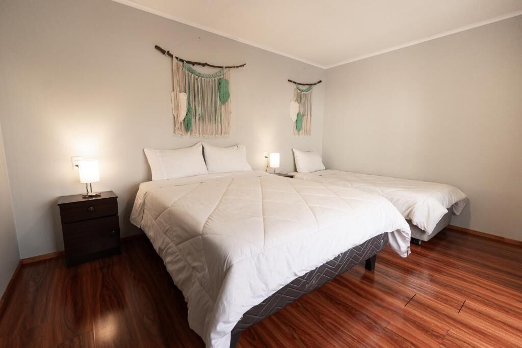 A bedroom with a large bed, two bedside tables, and wall-mounted macramé decorations.