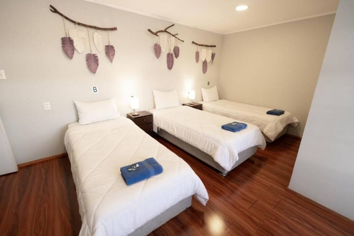 A hotel room with two beds, wooden flooring, and wall-mounted decorations.