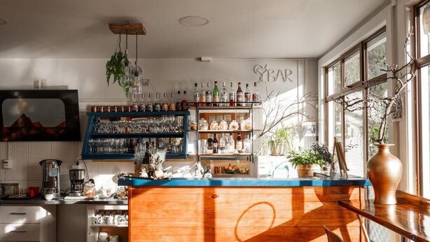 Eine Bar mit Regalen voller Flaschen, Gläsern und einer Holztresen.