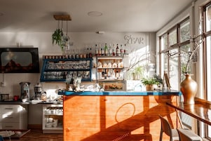 Zona de bar con estantes llenos de botellas, copas y un mostrador de madera.