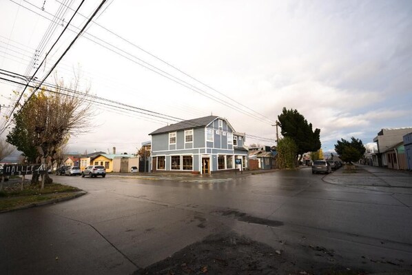 A street view with a two-story building, parked cars, and power lines.