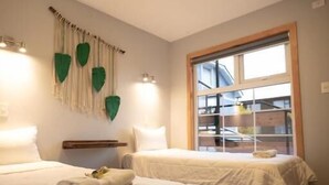 Ein Hotelzimmer mit zwei Betten, einem Fenster mit Jalousien und einer Wandleuchte.