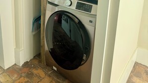 A laundry room with two stacked washing machines, a metal rack, and a brick floor. - Main Street House with private pool! (Bay St. Louis)