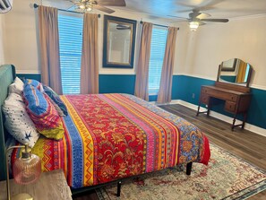 A bedroom with a bed, a dresser, a mirror, and a ceiling fan.
