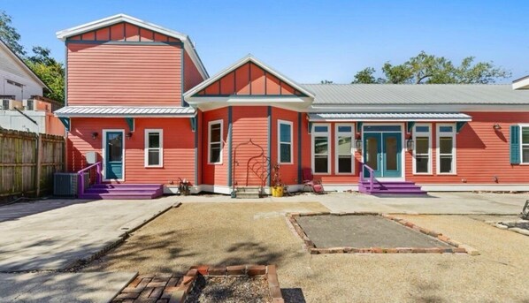 A red building with a porch and a fire pit in the yard.