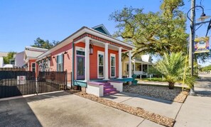 A single-story house with a porch, a gated driveway, and a street lamp. - Main Street House with private pool! (Bay St. Louis)