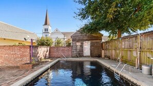 A swimming pool with a wooden deck and a brick wall. - Main Street House with private pool! (Bay St. Louis)