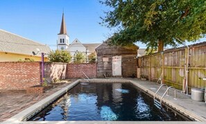 Ein Schwimmbecken mit Holzterrasse und Backsteinmauer.